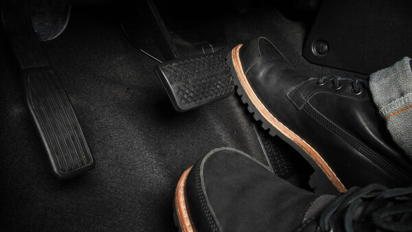 Человек ноги и акселератор и педаль тормоза внутри автомобиля или транспортного средства и копировать пространство, которое черный цвет кожи обувь наступил на него для ускорения или управления автомобильной мощности темпа. Концепция управления автомобилем