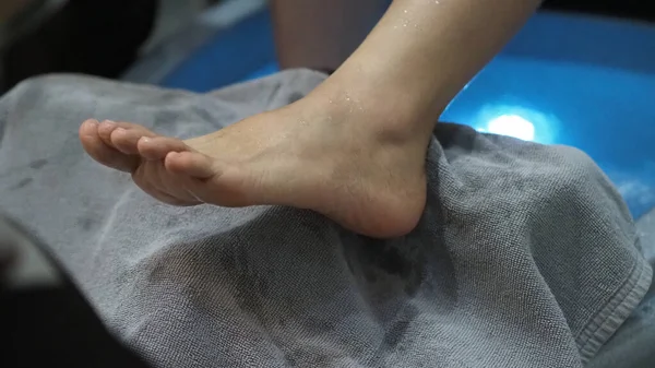 Foot Spa. Woman bare feet massaging in soap water machine at spa shop. Feet of women entering the footbath in the hot water handheld