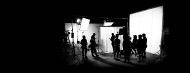 Silhouette images of film production. behind the scenes or b-roll of making video commercial movie. Film crew lightman and cameraman working together with film director in studio. Film industry. clipart