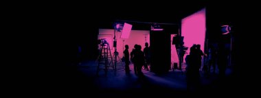 Silhouette images of film production. behind the scenes or b-roll of making video commercial movie. Film crew lightman and cameraman working together with film director in studio. Film industry.