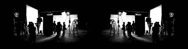 Silhouette images of film production. behind the scenes or b-roll of making video commercial movie. Film crew lightman and cameraman working together with film director in studio. Film industry.