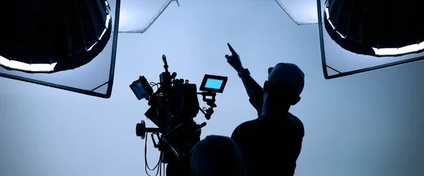 幕后录像制作 制作电视商业电影 由电影摄制组的光人和摄影师与电影导演在演播室一起工作 电影制作概念 轮廓风格 — 图库照片