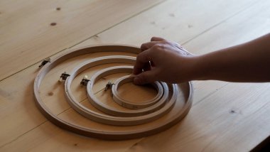 Kadın eli ve el işi. Elle işlenmiş nakış. El işi iplik iğnesiyle örülmüş. Tahta çerçeve nakışlı halka. İğne işi el işi karantina eğlence konsepti. 