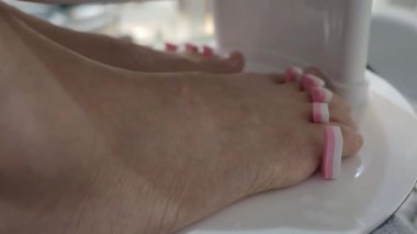 Ayak bakımı. Kadın çıplak ayakla masaj yapıyor ve kaplıcada manikür yaptırıyor. Ayak parmakları manikürcüye giriyor. El kamerası. Kaplıca salonunda yağ ile ayak masajı. Cilt sağlık hizmetlerini gevşetin. 
