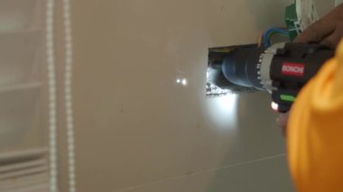 Profesyonel bir elektrikçinin elektrik prizi tamiri ve uzatma kabloları. Matkaplar, kablolar, sigortalar, yüzen kutular ve kablolar gibi ekipmanlarla. Duvar anahtarları ve soketleri yükleniyor.
