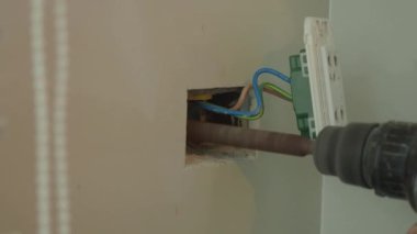 Profesyonel bir elektrikçinin elektrik prizi tamiri ve uzatma kabloları. Matkaplar, kablolar, sigortalar, yüzen kutular ve kablolar gibi ekipmanlarla. Duvar anahtarları ve soketleri yükleniyor.