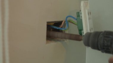 Profesyonel bir elektrikçinin elektrik prizi tamiri ve uzatma kabloları. Matkaplar, kablolar, sigortalar, yüzen kutular ve kablolar gibi ekipmanlarla. Duvar anahtarları ve soketleri yükleniyor.