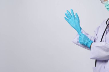 Eldiven takıyordu. Asyalı doktor mavi kauçuk nitril eldiven giyer. Maskeli doktor eldiven takıyor. izole edilmiş beyaz arkaplan kopyalama alanı. Sağlık koruma koronovirüs salgını konsepti.