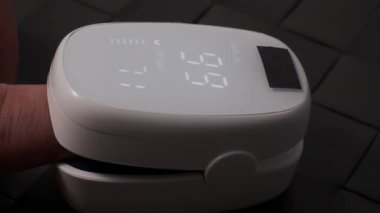 Oksimetre kullanımı. Nabız oksimetresi, nabız ve oksijen seviyelerini ölçmek için kullanılır. Covid 19 salgını sırasında evde bakım. Sağlık hizmeti izleme konsepti. Taşınabilir parmak ucu nabız oksimetresi kullanıyor. 4k