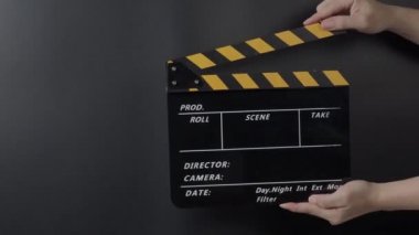 Film tahtası ya da alkış tahtası vuruşu. El ele tutuşup boş film sayfasını kapayarak siyah arkaplanda alkışlıyoruz. Video prodüksiyonu için açık ve kapalı film sayfası. Film yapımcılığı. Film çekimi.
