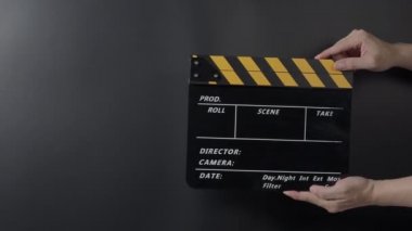 Film tahtası ya da alkış tahtası vuruşu. El ele tutuşup boş film sayfasını kapayarak siyah arkaplanda alkışlıyoruz. Video prodüksiyonu için açık ve kapalı film sayfası. Film yapımcılığı. Film çekimi.