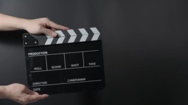 Film tahtası ya da alkış tahtası vuruşu. El ele tutuşup boş film sayfasını kapayarak siyah arkaplanda alkışlıyoruz. Video prodüksiyonu için açık ve kapalı film sayfası. Film yapımcılığı. Film çekimi.