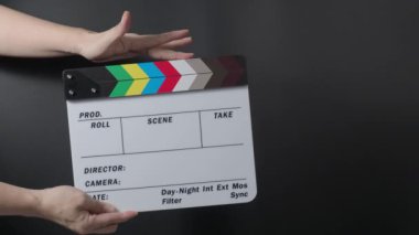 Film tahtası ya da alkış tahtası vuruşu. El ele tutuşup boş film sayfasını kapayarak siyah arkaplanda alkışlıyoruz. Video prodüksiyonu için açık ve kapalı film sayfası. Film yapımcılığı. Film çekimi.