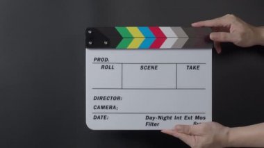 Film tahtası ya da alkış tahtası vuruşu. El ele tutuşup boş film sayfasını kapayarak siyah arkaplanda alkışlıyoruz. Video prodüksiyonu için açık ve kapalı film sayfası. Film yapımcılığı. Film çekimi.