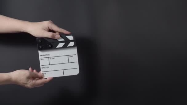 映画のスレートやクラッパーボードのヒット 手を閉じて空のフィルムスレートを保持し 黒の背景にそれを拍手 ビデオ制作のためにフィルムスレートを開いて閉じます 映画製作です 映画撮影 — ストック動画