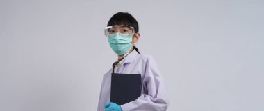 Üniformalı doktor boş bir bölgeyi işaret ediyor. Salgın virüsünü önlemek için mavi lateks eldivenler, temiz gözlükler ve yeşil N95 maskesi takıyor. Asyalı doktor. El hareketi. Tıbbi steteskop. Virüs Kitabı