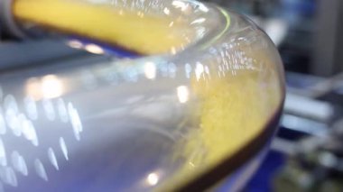 Plastik topaklar hava tüpleri. Otomatik makinede sarı plastik topaklar taşıyan saydam endüstriyel tüpü kapatın. Yüksek hızda hareket eden mühendislik materyali. Plastik üretim teknolojisi