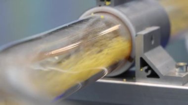 Plastik topaklar hava tüpleri. Otomatik makinede sarı plastik topaklar taşıyan saydam endüstriyel tüpü kapatın. Yüksek hızda hareket eden mühendislik materyali. Plastik üretim teknolojisi