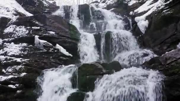 Cascada de invierno en las montañas. El agua rompe la nieve y el hielo — Vídeo de stock