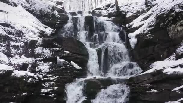 Cascada de invierno en las montañas. El agua rompe la nieve y el hielo — Vídeos de Stock
