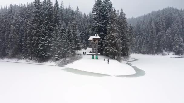 Vista aérea del bosque congelado con el lago cubierto de nieve en invierno en las montañas de los Cárpatos — Vídeos de Stock