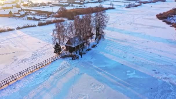 Vue aérienne d'une petite maison sur l'île. Paysage hivernal avec un pont vers la maison sur le lac. — Video