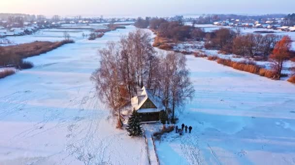 Vista aérea de una pequeña casa en la isla. Paisaje invernal con un puente a la casa en el lago. — Vídeo de stock