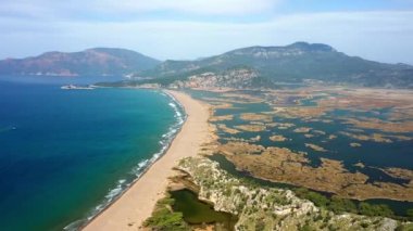 Uzun plaj muhteşem dağları sazlıklar, dalgalı deniz manzarası. İztuzu plajı Mugla, Dalyan köyü, Türkiye. 4K video