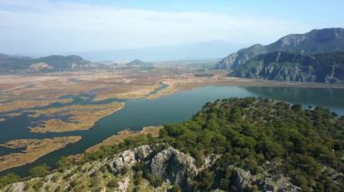 Uzun plaj muhteşem dağları sazlıklar, dalgalı deniz manzarası. İztuzu plajı Mugla, Dalyan köyü, Türkiye. 4K video