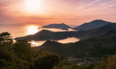 Oludeniz, Türkiye 'de güzel bir gün batımı olan Blue Lagoon' un muhteşem hava manzarası. Plajlı ve dağlı yaz manzarası, yeşil orman, gök mavisi su, kumlu sahil ve açık güneşli bir günde mavi gökyüzü en iyi turist.