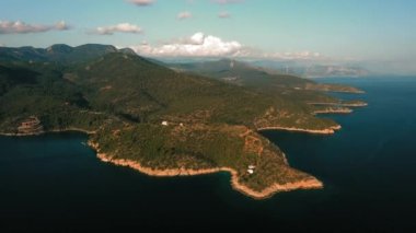 Okyanus mavi dalgalarının insansız hava aracının 4K görüntüsü kayalık bir dağın yüksek uçurumunda kırılıyor. Sahilde tehlikeli deniz dalgaları