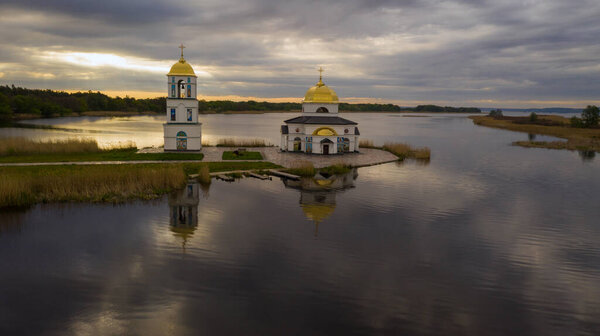 Church on the water in the rays of the rising sun