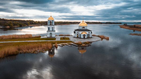 Church on the water in the rays of the rising sun