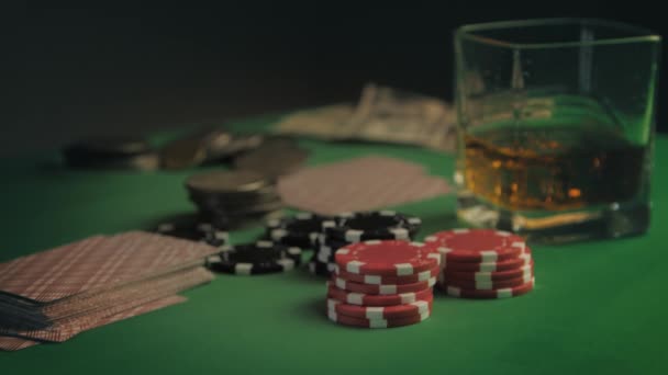 Fichas, tarjetas, un vaso de whisky y dinero están en la mesa de juego verde. El jugador hace la apuesta. Primer plano. Fondo de juego — Vídeos de Stock