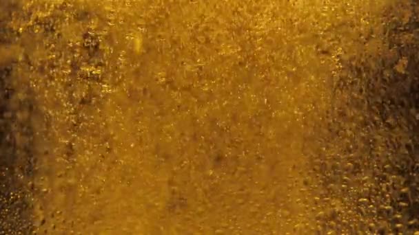 Макро выстрел тонких пузырьков, растущих в стакане с апельсиновой жидкостью. Медленное движение, лоск рябины пивных пузырей и пены в стекле — стоковое видео