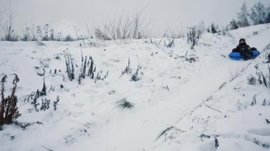 Kış Parkı 'nda tüpün üstünde kayan bir çocuk. Kışın eğlence parkında kar kayması. Yavaş çekim.