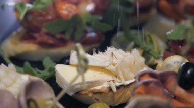 Pişmiş yemeğin üzerine peynir serpiştirilmiş jambon dilimleri serpiştirilmiş.