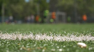 Bulanık koçu olan yeşil yapay sahaya seçici odak, top ve futbol eğitim ekipmanlarıyla çocuk oyunculara koçluk yapıyor. Futbol akademisinde bulanık arkaplan futbol eğitimi.