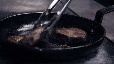 Izgara tavasında hazırlanmış büyük, sulu bir parça taze et. Şef evde yemek pişirmek için bifteği maşayla pişiriyor. Buhar ve duman kızgın tavanın üzerinde yükselir. Başlangıç Aşçıları Günlük Kaydı