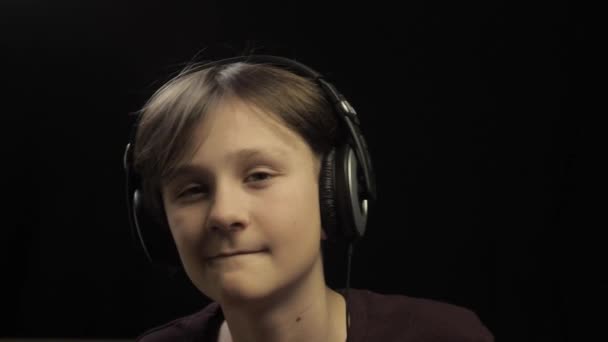 Tonåring lyssnar musik i hörlurar och dansa över mörk studio bakgrund — Stockvideo