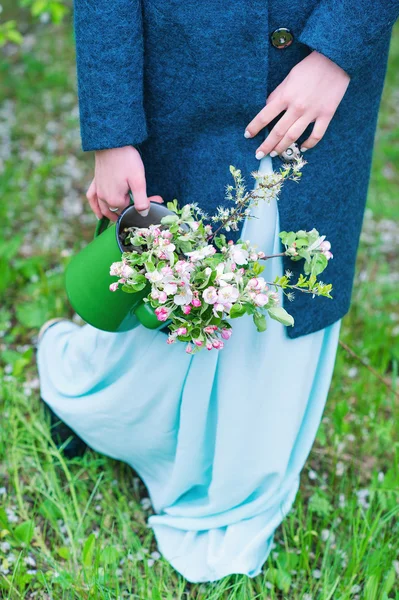 Kvinna som bär långtidsvattnande kruka med blommande grenar — Stockfoto