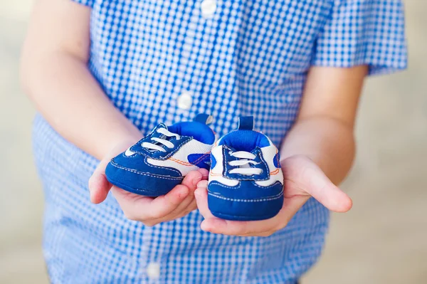 Хлопчик тримає своїх братів крихітні чоботи — стокове фото