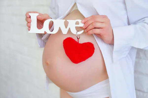 Těhotná žena drží znamení lásky — Stock fotografie