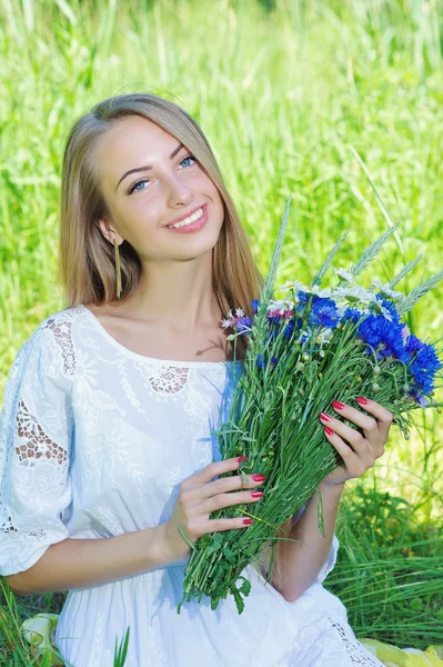 Gelukkige vrouw met bouquet van chamomiles en korenbloemen — Stockfoto