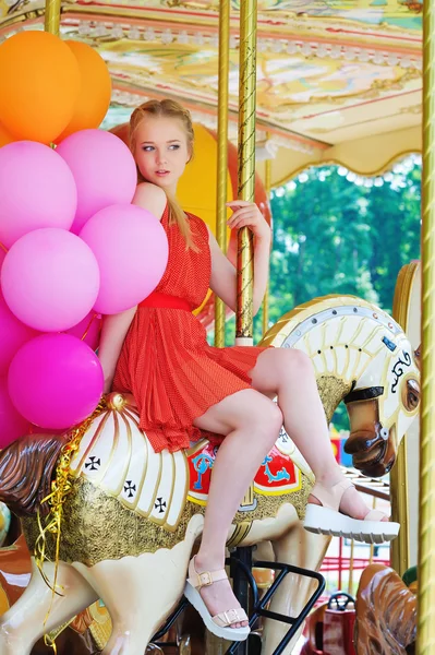 Jeune femme modèle chevauchant un carrousel — Photo