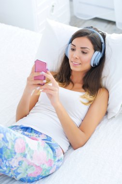 Kulaklıklı güzel genç bir kadın müzik dinliyor.