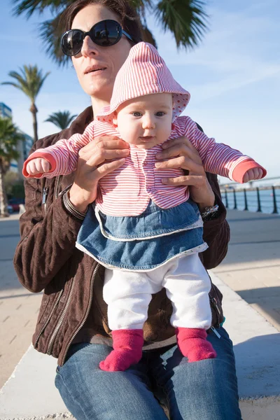 Bebê de pé na mãe pernas na rua — Fotografia de Stock