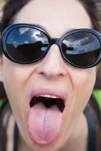 Kobieta z okulary wystaje jej język — Zdjęcie stockowe