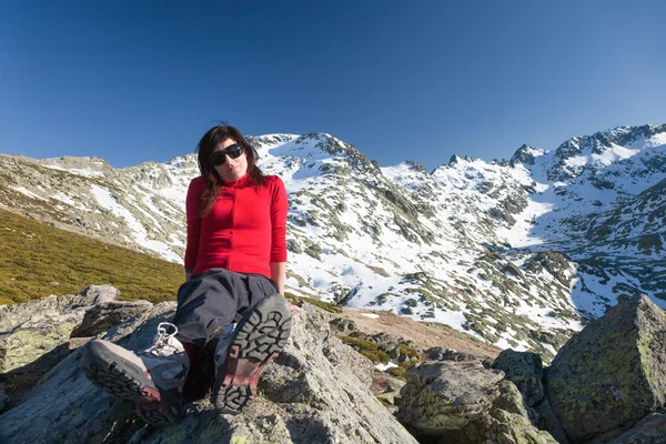 Vermelho casaco de lã mulher sentada posando no pico das montanhas — Fotografia de Stock