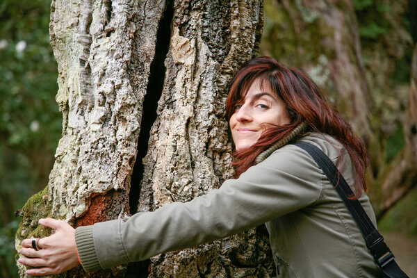 улыбающаяся женщина обнимает дерево
